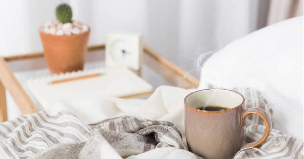 cup-of-coffee-on-cozy-white-bed-picture-id664529448